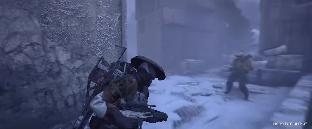 Player in a wide-brimmed helmet holding a rifle against a frosted wall while another player crosses a snowy street ahead
