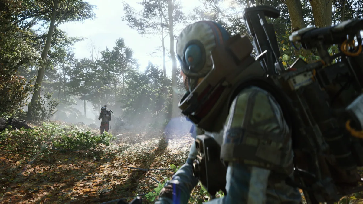 A Raider in helmet and backpack moves through a misty forest clearing at dawn, with a second Raider visible in the distance ahead