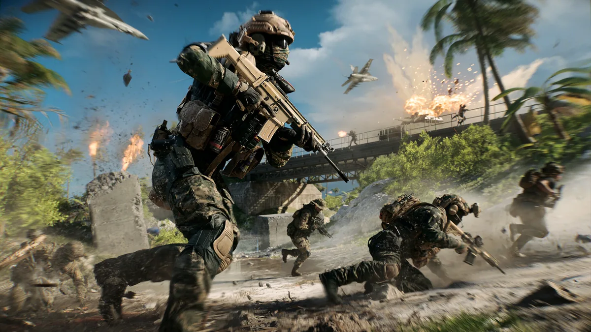 A tropical beach combat scene with soldiers running past palm trees and a burning bridge, jets visible overhead against a blue sky