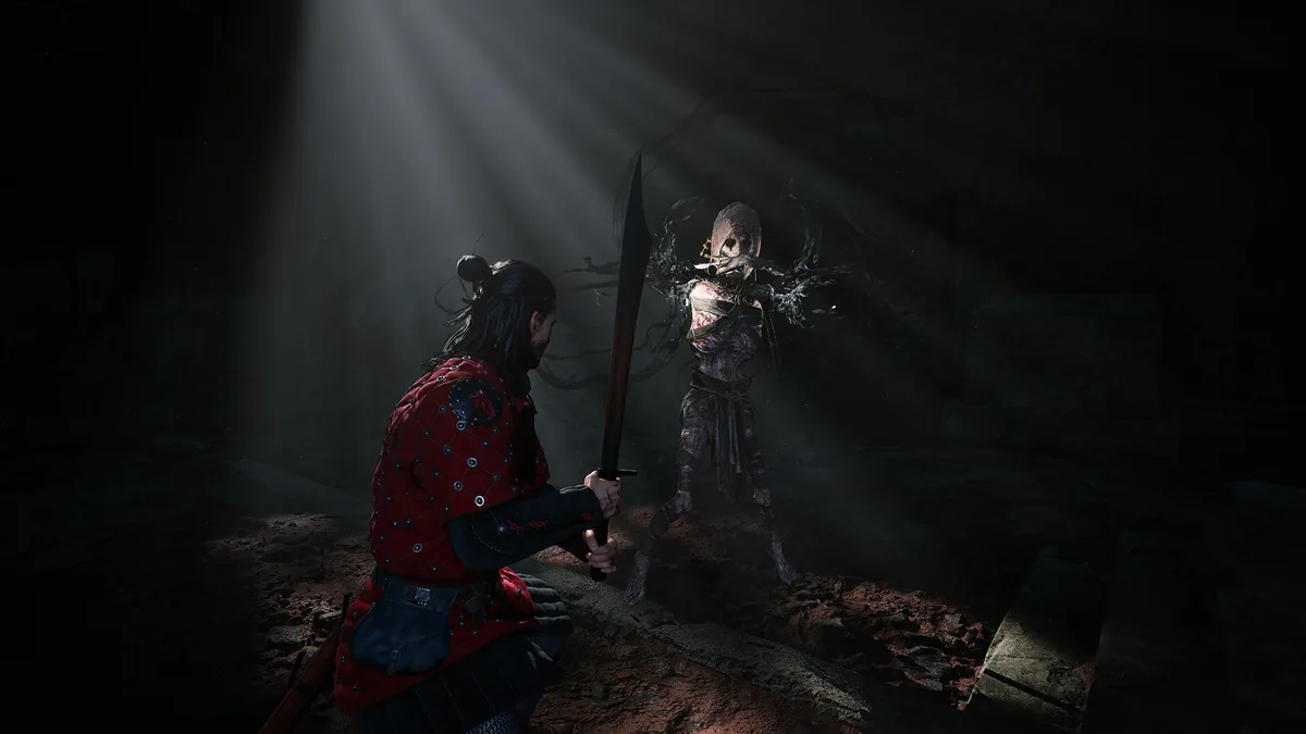 Coen crouched in a shadowy dungeon raising a sword against a bandaged, undead-looking humanoid creature illuminated by a single shaft of light