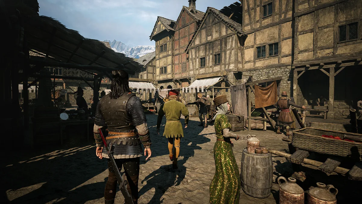 Coen walking through a lively medieval market street lined with half-timbered buildings and market stalls, with mountains visible in the distance