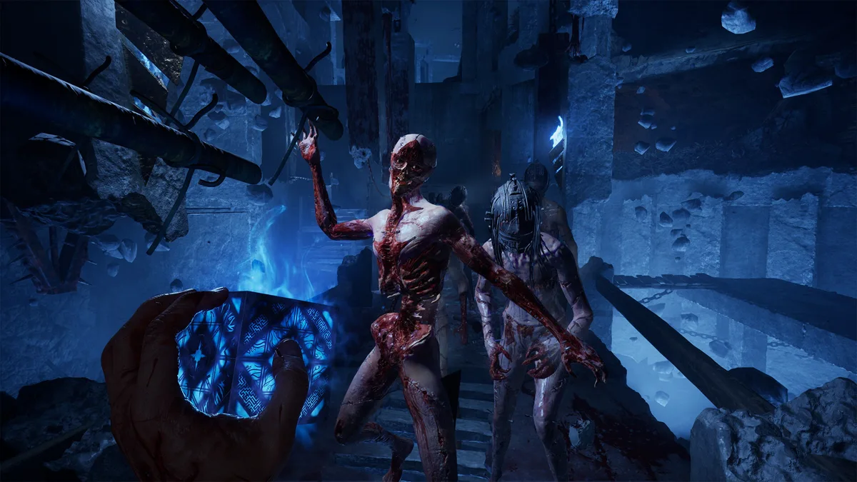 Glowing blue puzzle box raised toward two skinless creatures in a ruined stone chamber