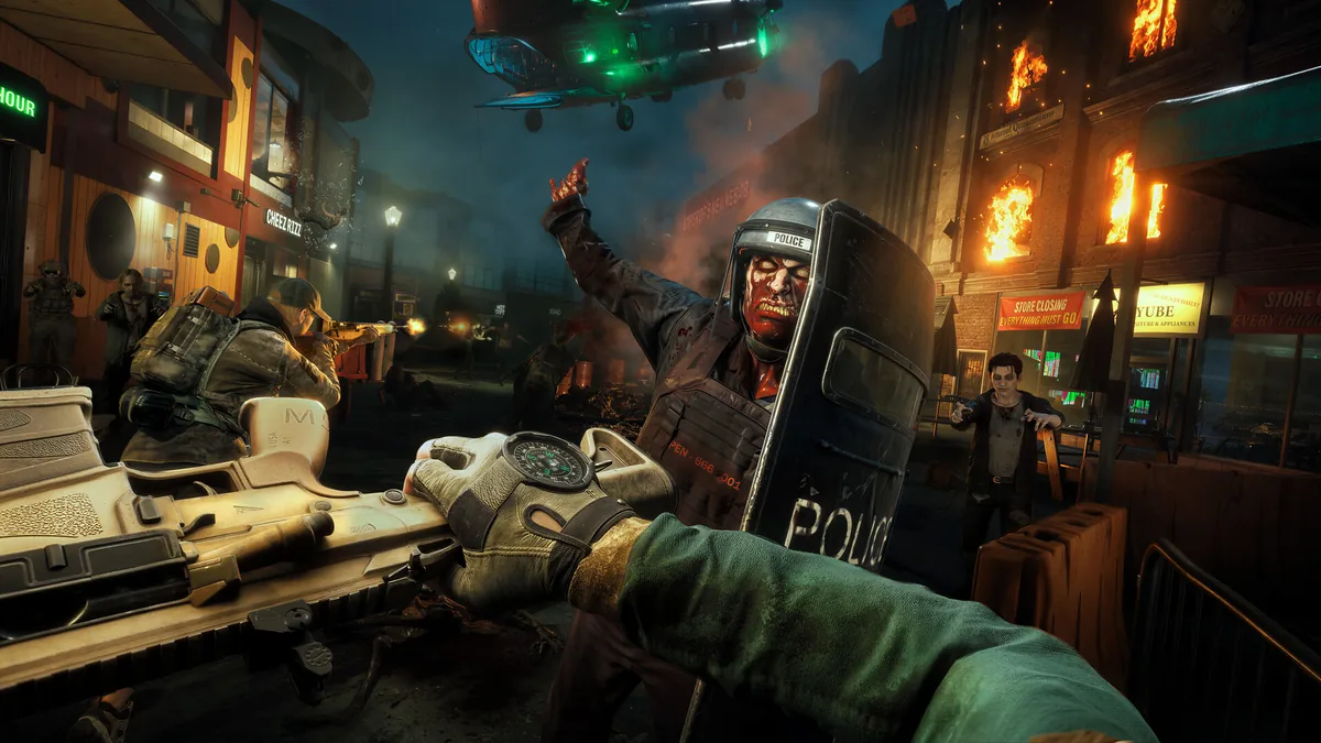 First-person view of a Responder aiming a rifle at a zombified police officer holding a riot shield, with an extraction helicopter descending over a burning street