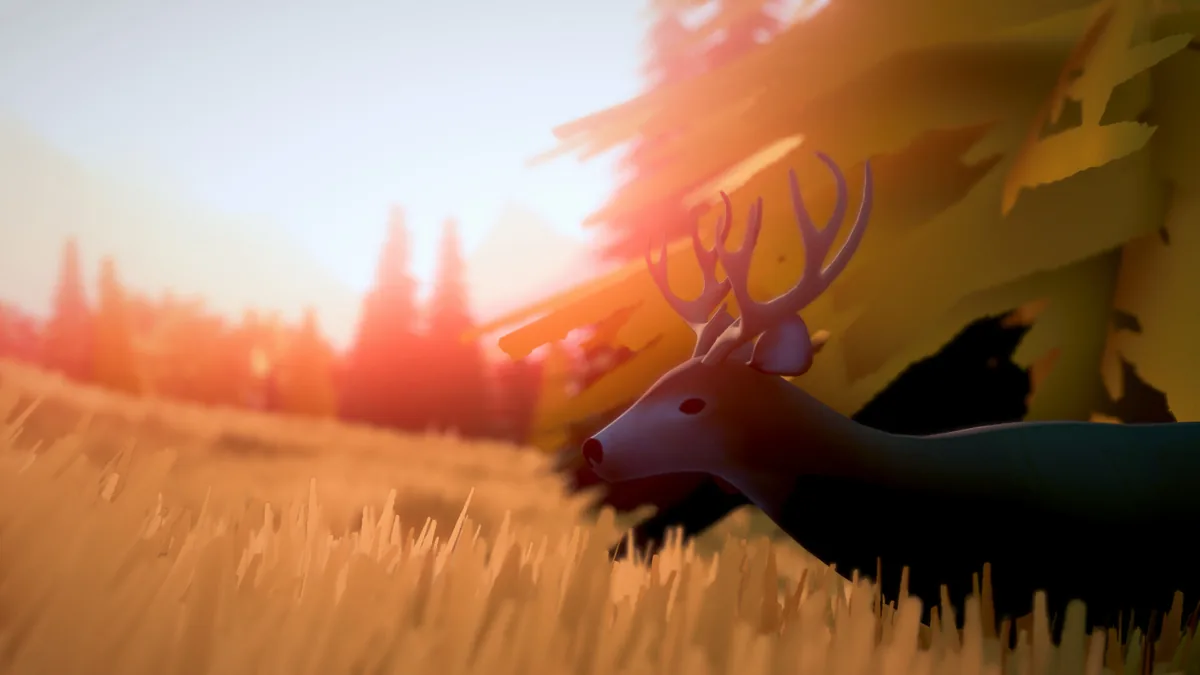 Close view of a deer with antlers in a golden grassy field beneath a hazy sunset