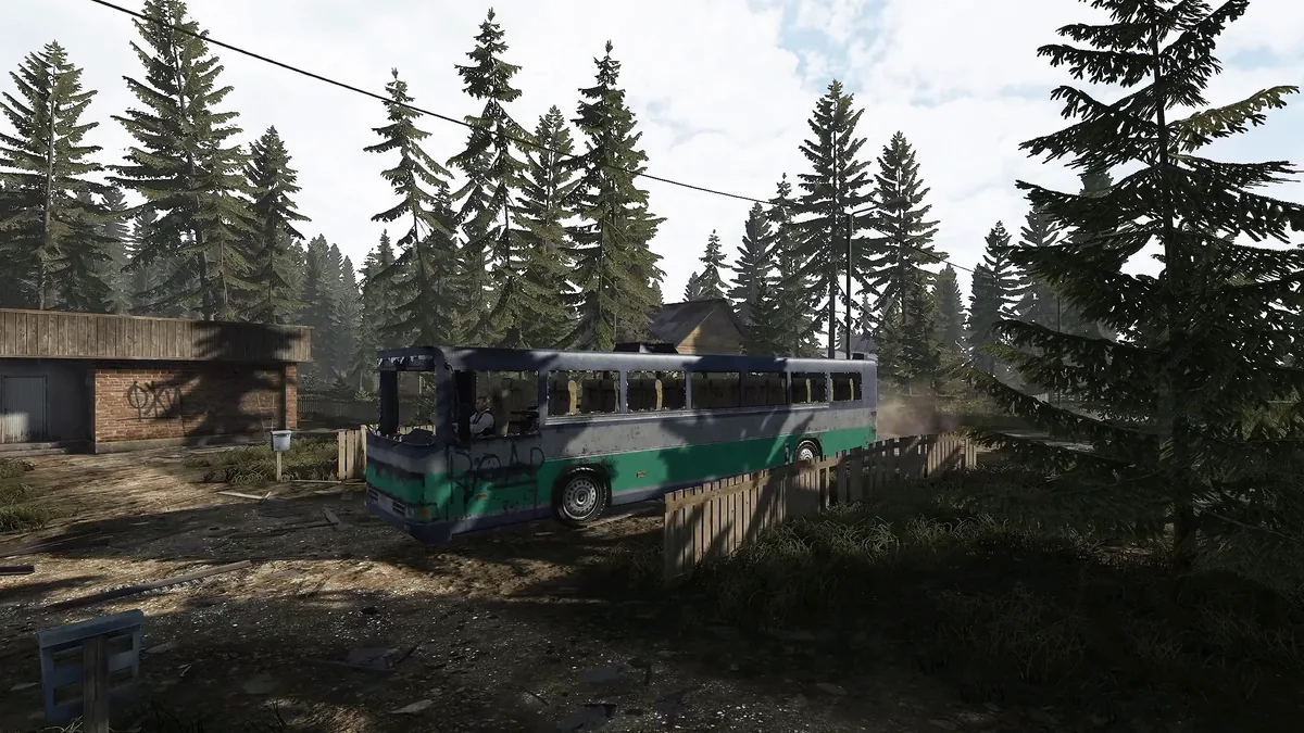 A green and white bus parked on a dirt road between pine trees and a brick garage in Road to Vostok