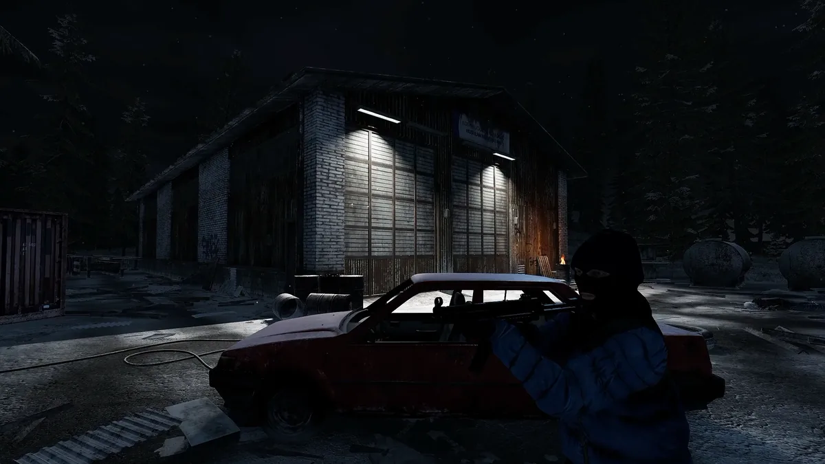 Night view of the Garage shelter, a brick and corrugated-metal building with lit windows, a red car parked outside and a masked, armed figure in the foreground