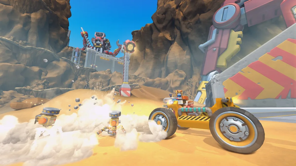 A yellow excavator vehicle drives through the new desert biome as small robots scatter in dust clouds, a larger red robot visible near a striped structure in the background