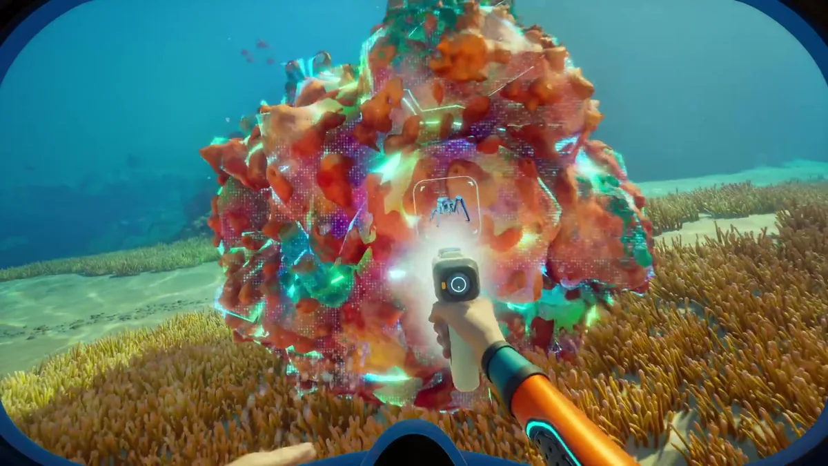 Diver aiming a scanner tool at a large orange and teal resource formation on a shallow reef, targeting reticle active