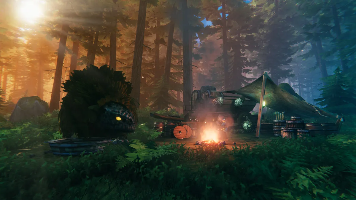 Valheim early camp at dusk showing a workbench, lit campfire, tent shelter, and a shield leaning nearby with a strange nearby creature