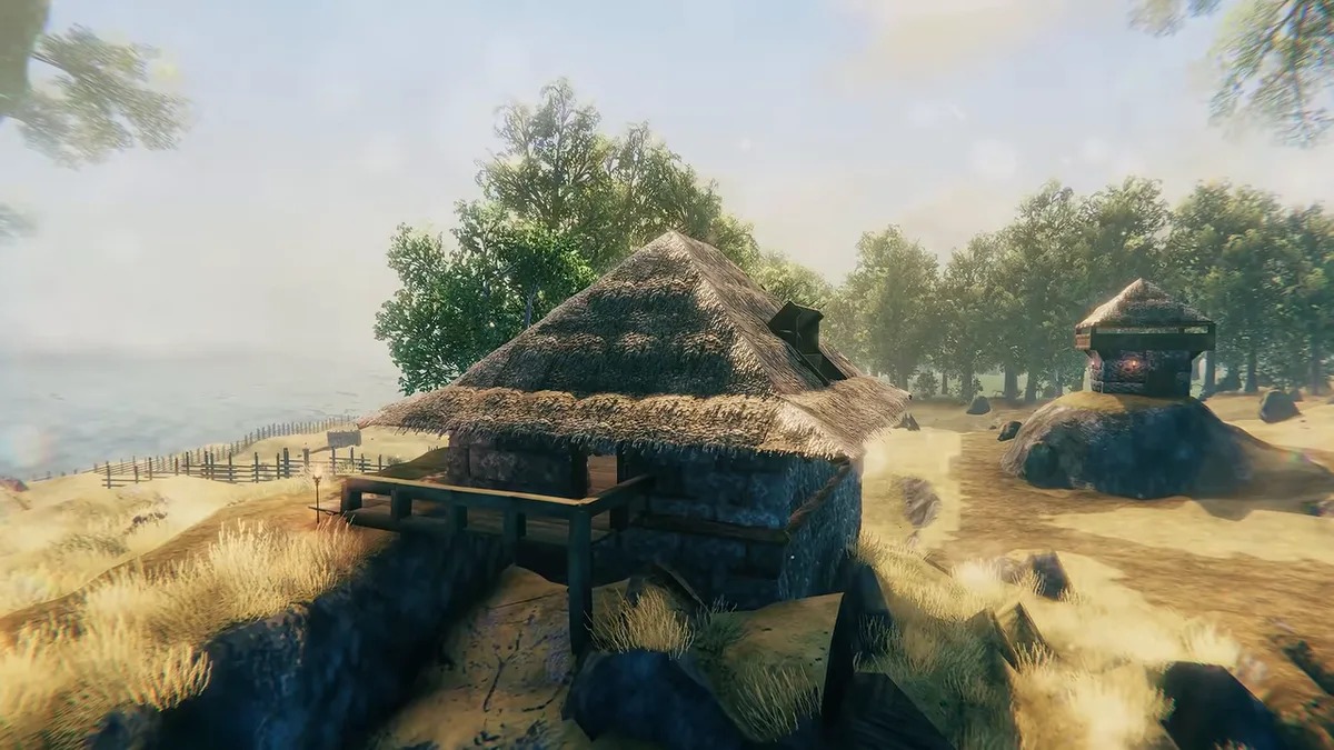 Valheim trailer frame of a thatched cottage on a dry grassy coast, with a small shrine and trees behind it