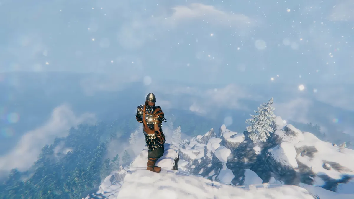 A Viking in plate armour stands on a snowy mountain peak above clouds and frosted pines