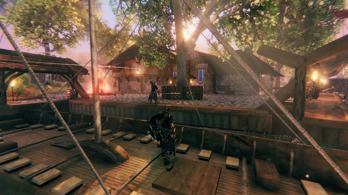 A torch-lit Viking village with a longhouse, a cobbled square and a warrior standing on a wooden ship deck in the foreground