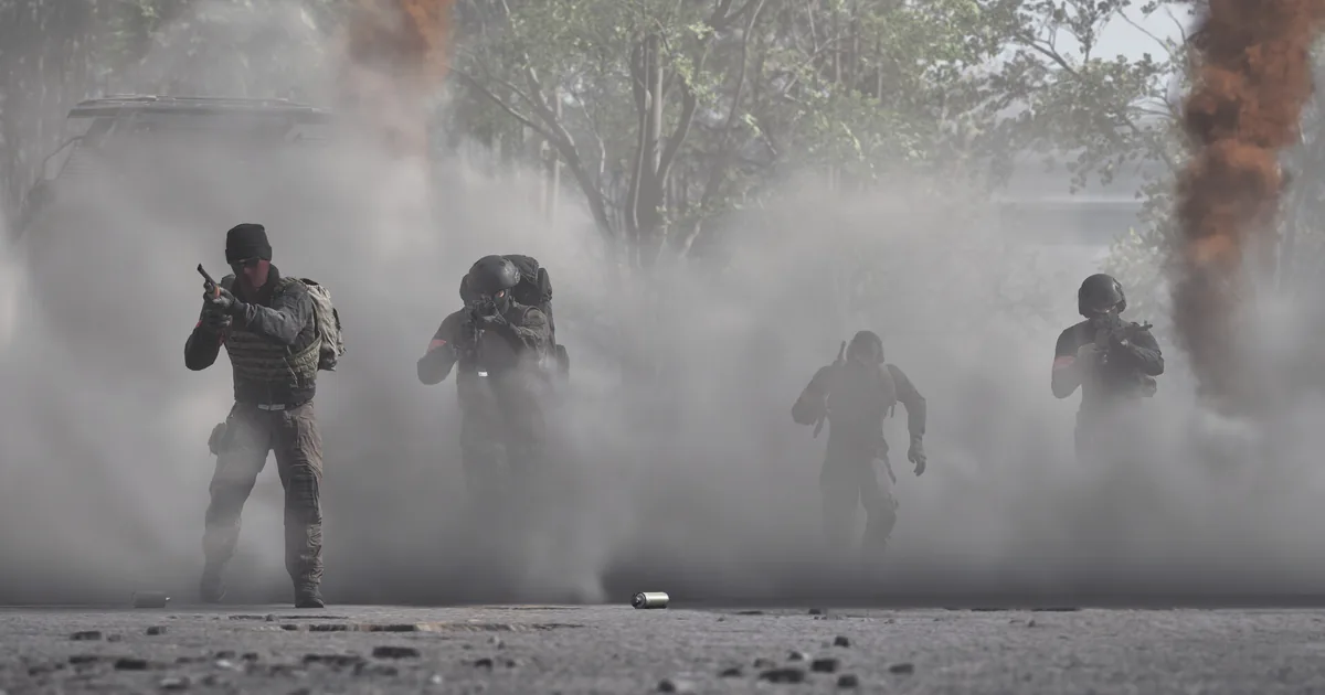 Four WARDOGS soldiers advancing through orange and grey smoke grenade cover on a debris-covered street