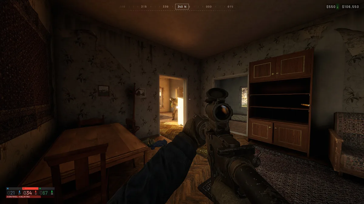 A first-person view inside a house shows a rifle aimed through a doorway at a squadmate breaching into a sunlit room, with the HUD showing a cash balance and a Control Zone labeled Valkyra